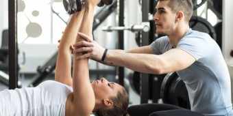 Fitness instructor exercising with his client at the gym